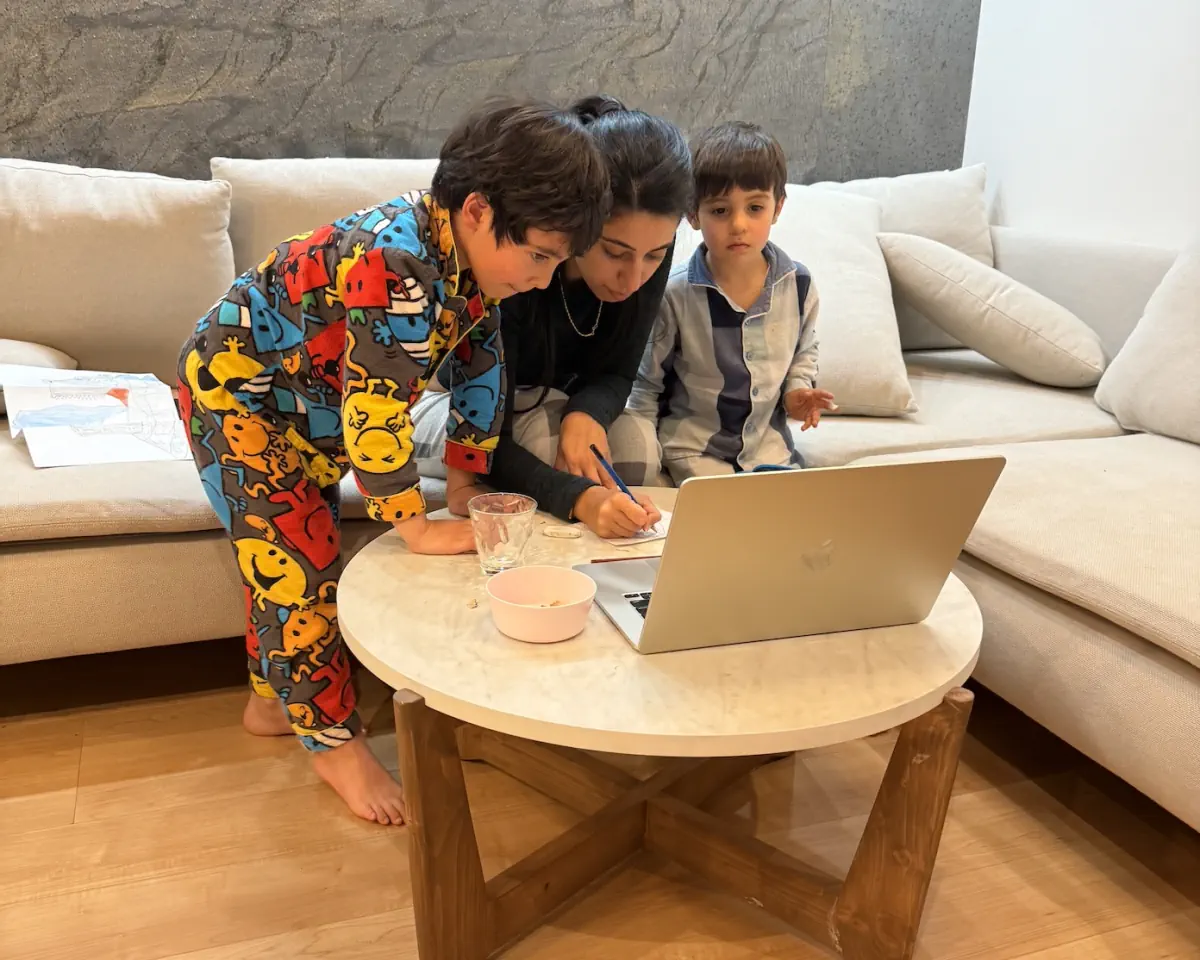 A parent helping two children learn at home